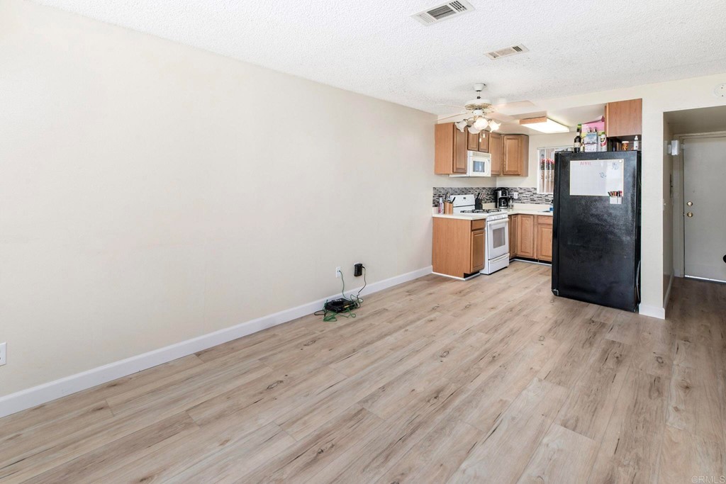 5130 North River Road, Unit F Oceanside, CA 92057 - Photo 3 of 15 a kitchen with granite countertop a refrigerator and a stove top oven