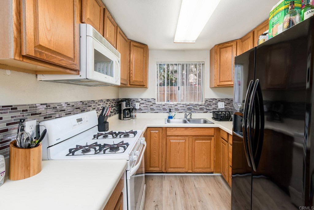 5130 North River Road, Unit F Oceanside, CA 92057 - Photo 4 of 15 a kitchen with stainless steel appliances granite countertop a refrigerator a sink dishwasher a stove and white countertops with wooden floor