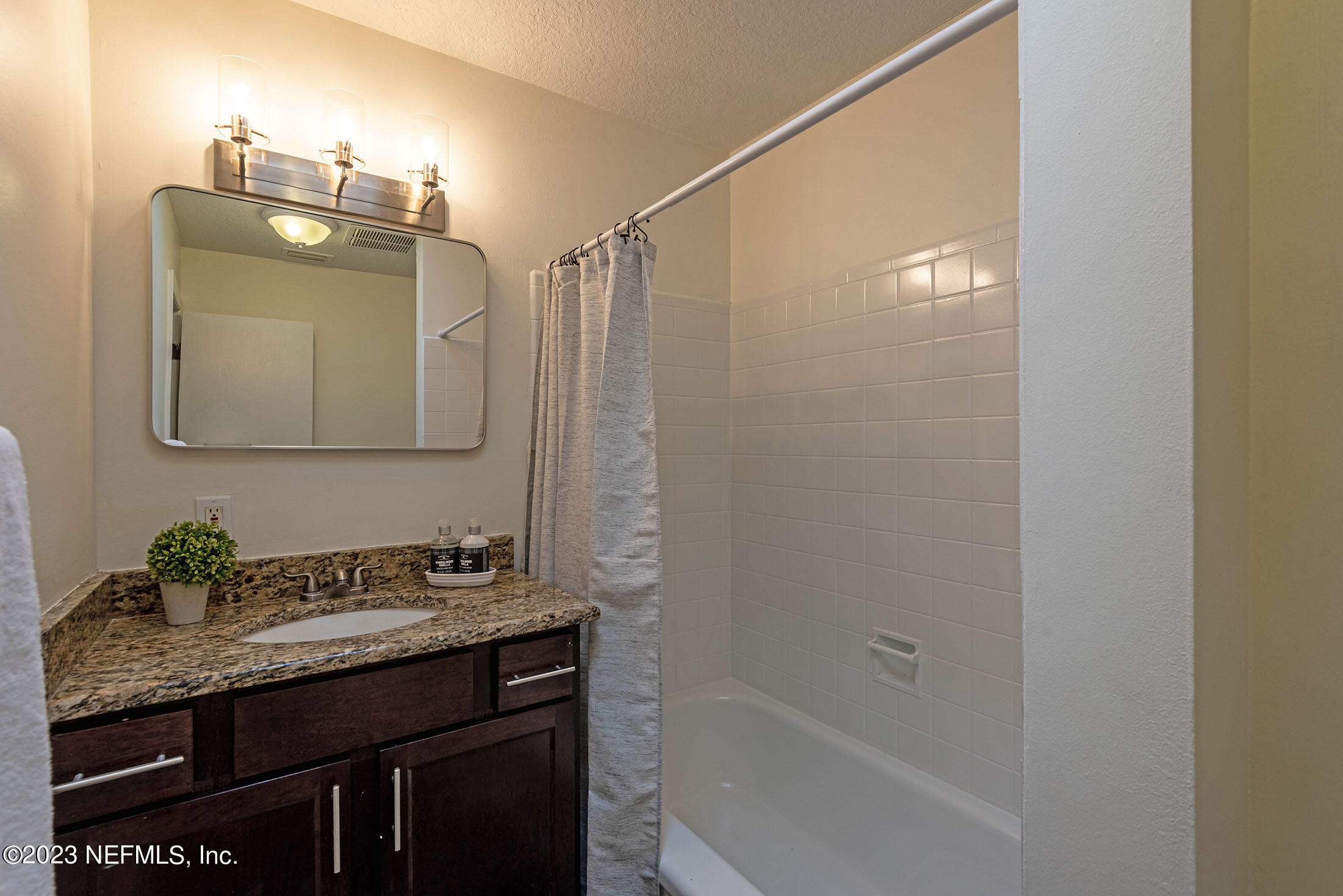 8007 Alderman Road Jacksonville, FL 32211 - Photo 30 of 63 a bathroom with a granite countertop sink a mirror and a bathtub