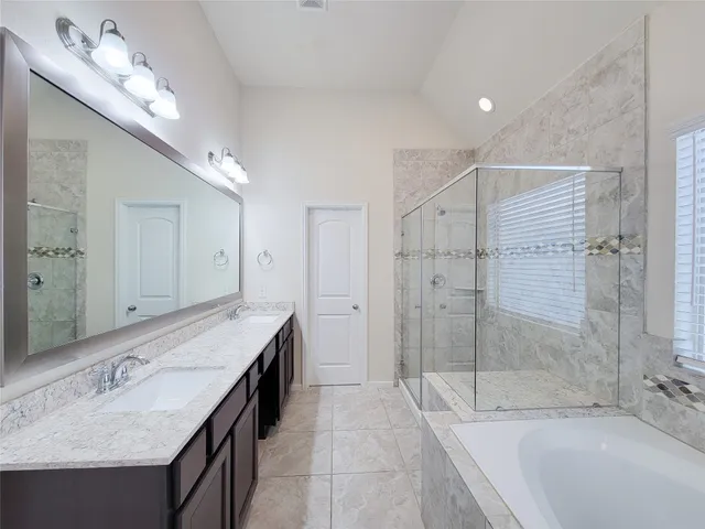 a spacious bathroom with a granite countertop sink a mirror a bathtub and shower