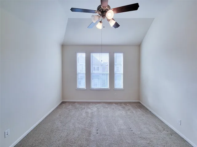 an empty room with a chandelier fan and windows