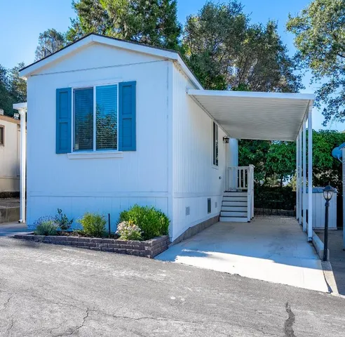 a view of a house with a yard plants and a table and chairs