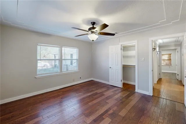 a view of an empty room with window and wooden floor