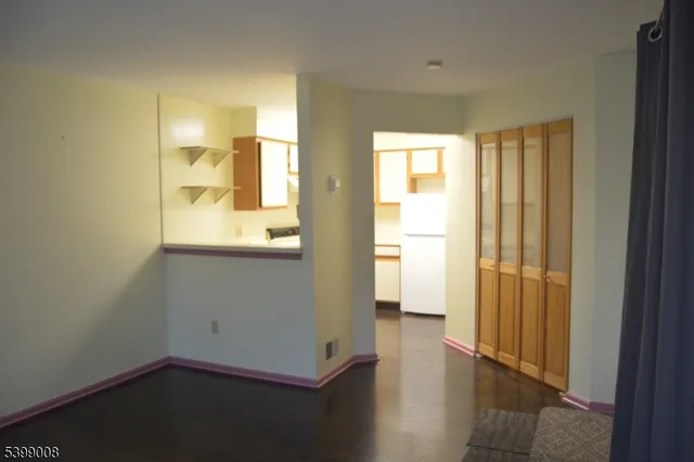 a view of a hallway with wooden floor and a bathroom