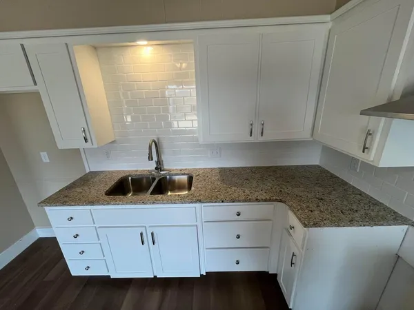 a kitchen with white cabinets and sink