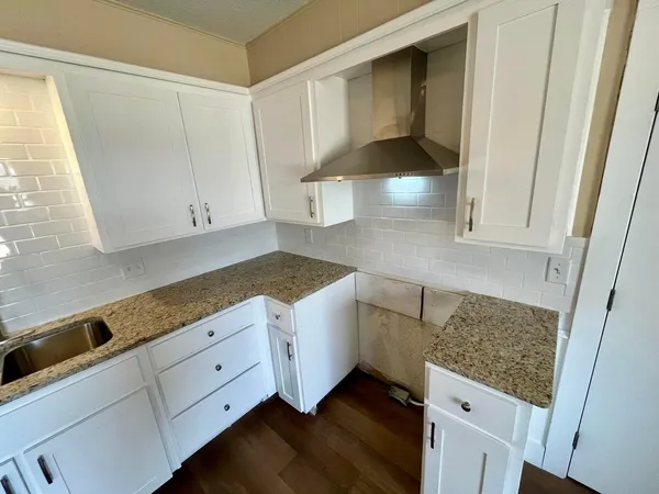 a kitchen with white cabinets and sink