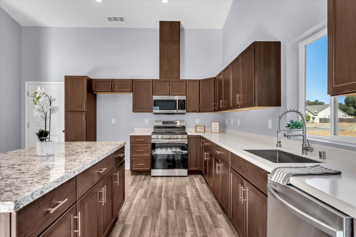 1565 Carl Court Red Bluff, CA 96080 - Photo 16 of 49 a kitchen with kitchen island granite countertop a sink stove and refrigerator