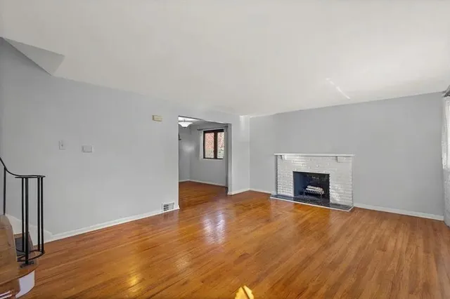 a view of empty room with wooden floor and fireplace
