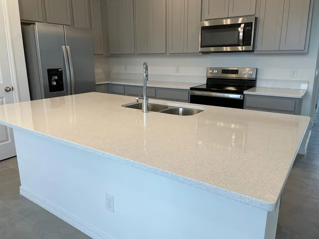 a kitchen with stainless steel appliances a refrigerator a sink a stove a microwave and cabinets