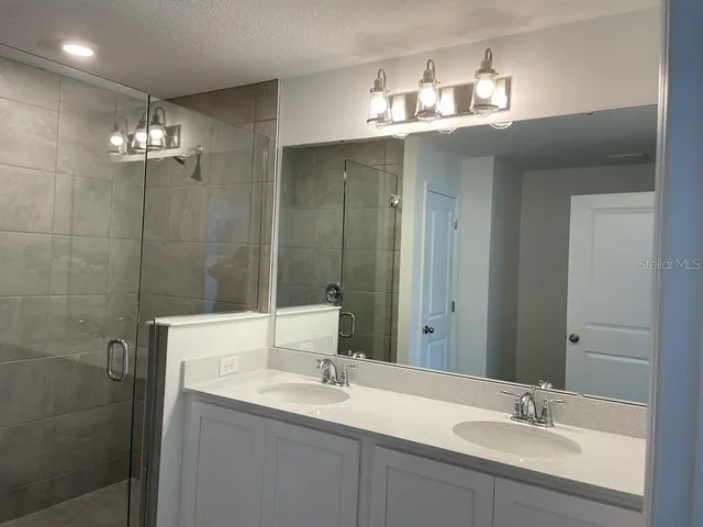 a bathroom with a shower sink and mirror