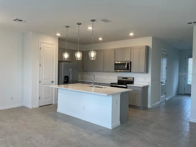 a large kitchen with stainless steel appliances granite countertop a sink a stove and a refrigerator