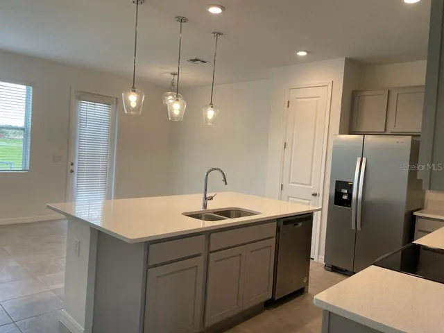 a kitchen with stainless steel appliances granite countertop a sink a refrigerator a center island and cabinets