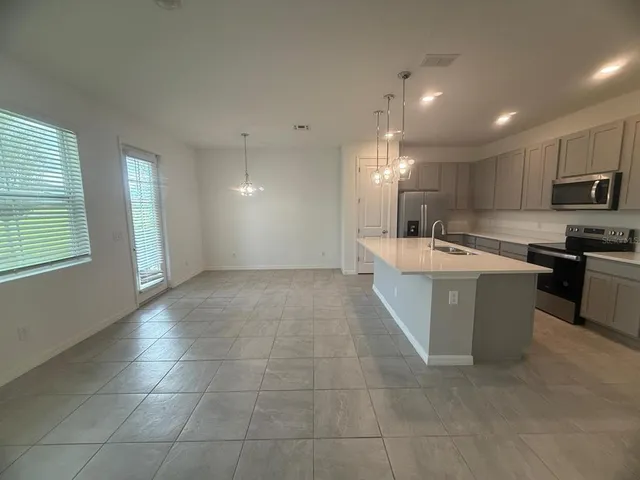 a large white kitchen with kitchen island a sink a stove a microwave and a refrigerator