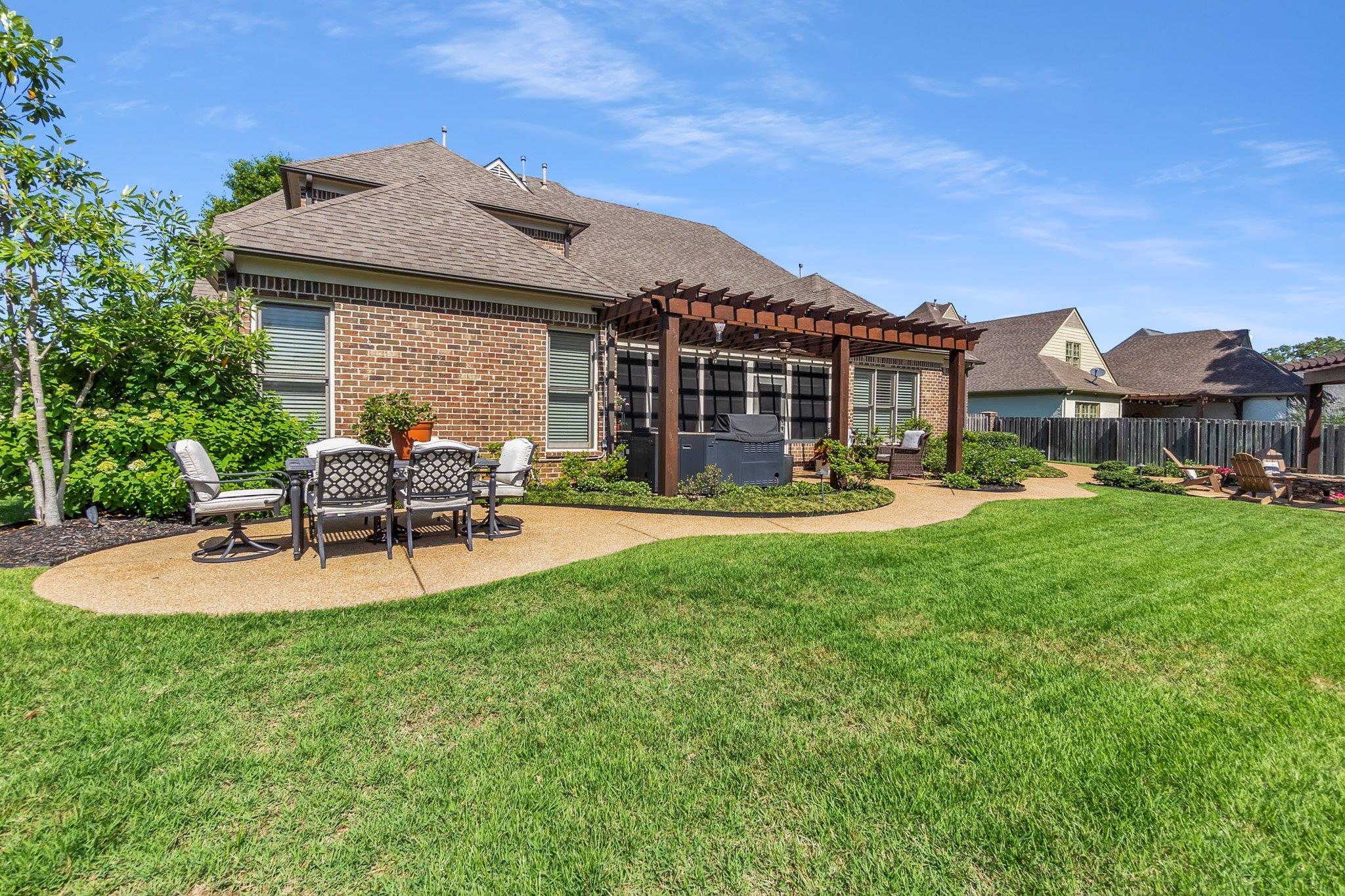 3246 North Hartwell Ridge Drive Collierville, TN 38017 - Photo 39 of 40 Expansive backyard featuring a manicured lawn, a large exposed aggregate patio, and a wood pergola