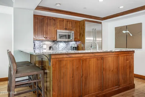 a kitchen with kitchen island granite countertop wooden cabinets and stainless steel appliances