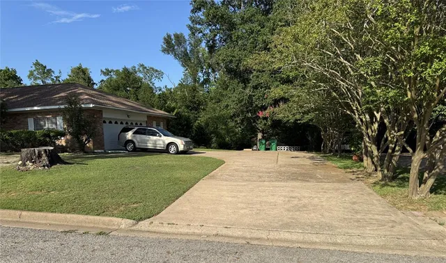 a view of a white house in front of a big yard with large trees