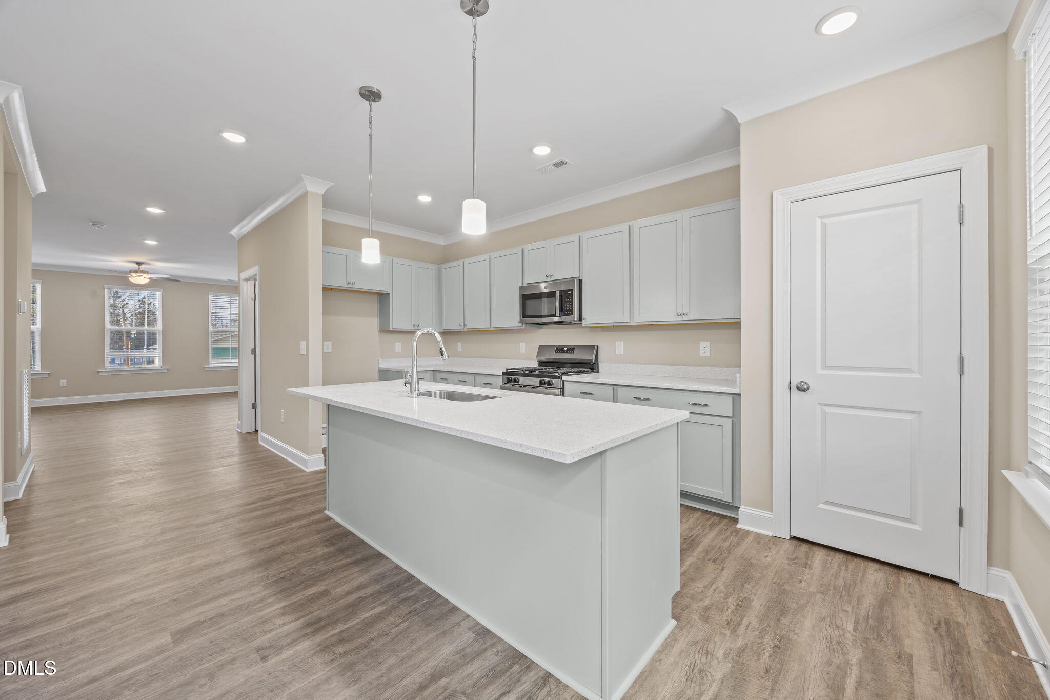 141 Pearl Street, Unit 9 Garner, NC 27529 - Photo 5 of 26 a kitchen with kitchen island a sink stainless steel appliances and white cabinets