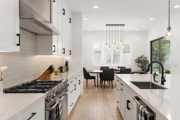a kitchen with stove a sink a kitchen island with chairs and wooden floor