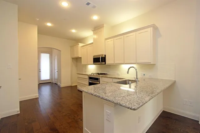 a kitchen with stainless steel appliances granite countertop a sink a stove and a refrigerator