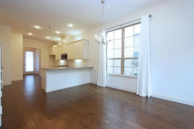a view of a kitchen and an empty room with wooden floor and a window