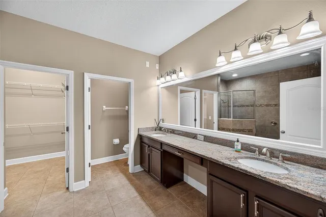 a bathroom with a granite countertop double vanity sink and a mirror