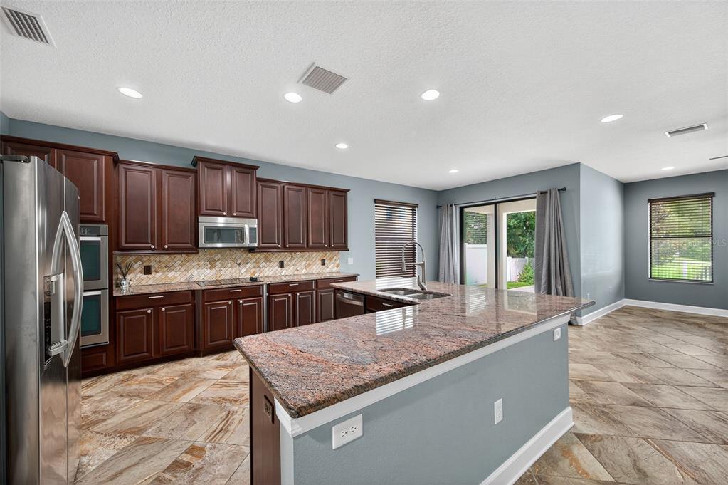 1120 Maza Place Trinity, FL 34655 - Photo 7 of 35 a kitchen with stainless steel appliances granite countertop a sink stove and refrigerator