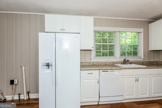 a kitchen with stainless steel appliances granite countertop white cabinets and window