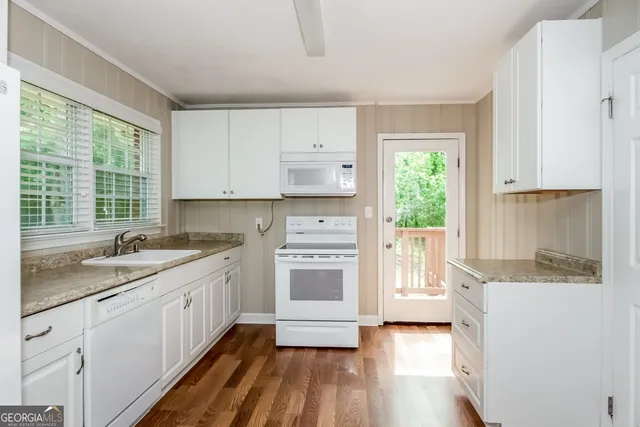 a kitchen with granite countertop white cabinets and white appliances
