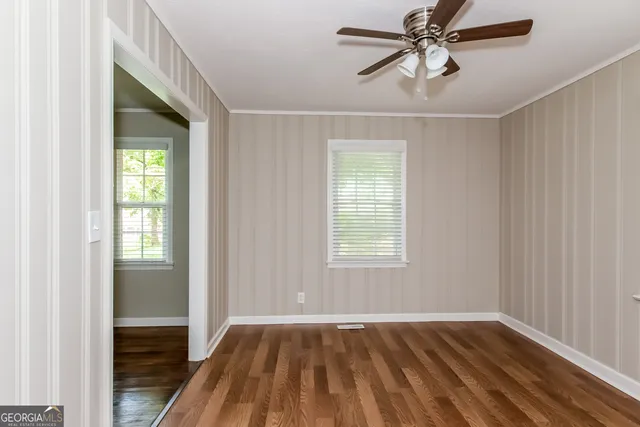 a view of empty room with wooden floor and fan