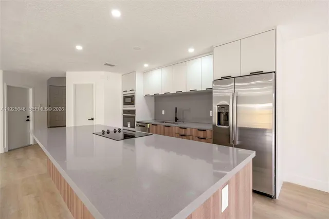 a large kitchen with kitchen island a large counter top space a sink stainless steel appliances and cabinets