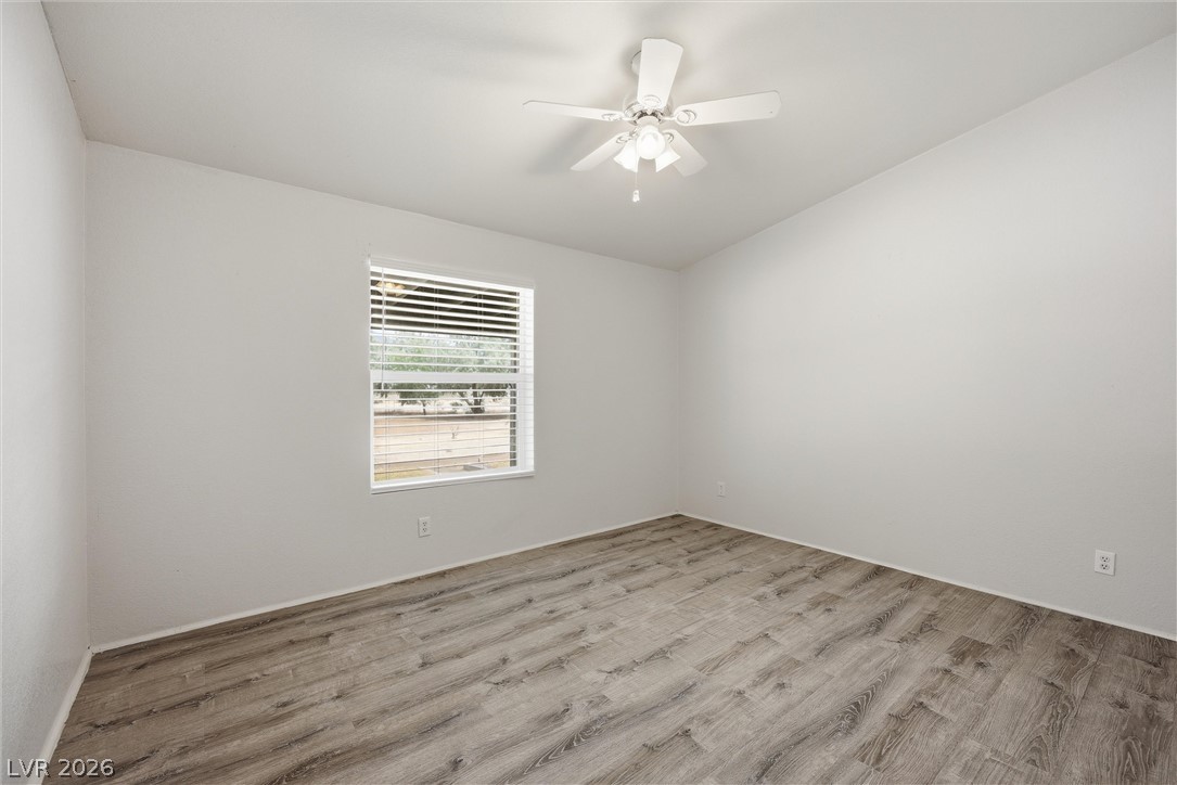 1531 West Harris Farm Road Pahrump, NV 89060 - Photo 32 of 37 A well-lit bedroom with modern wood-style flooring and a ceiling fan offers comfort and style.