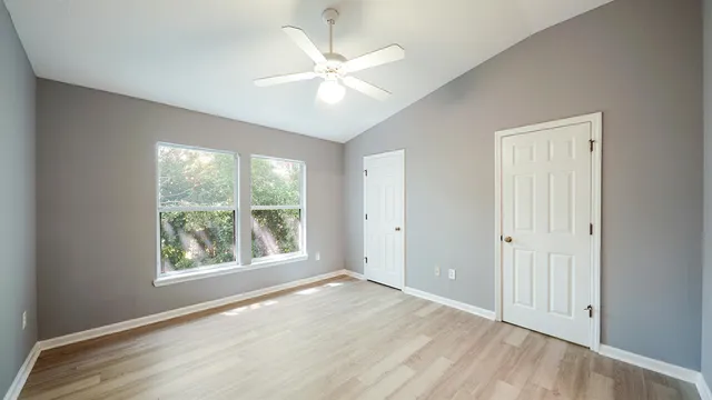 a view of an empty room with a window and wooden floor