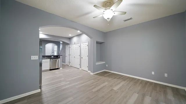 a view of a kitchen with a sink a ceiling fan and stainless steel appliances