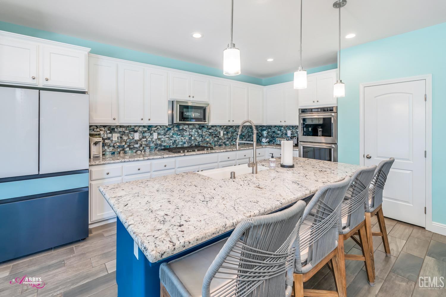Undisclosed Address Bakersfield, CA 93314 - Photo 15 of 40 a kitchen with stainless steel appliances kitchen island granite countertop a wooden table and chairs