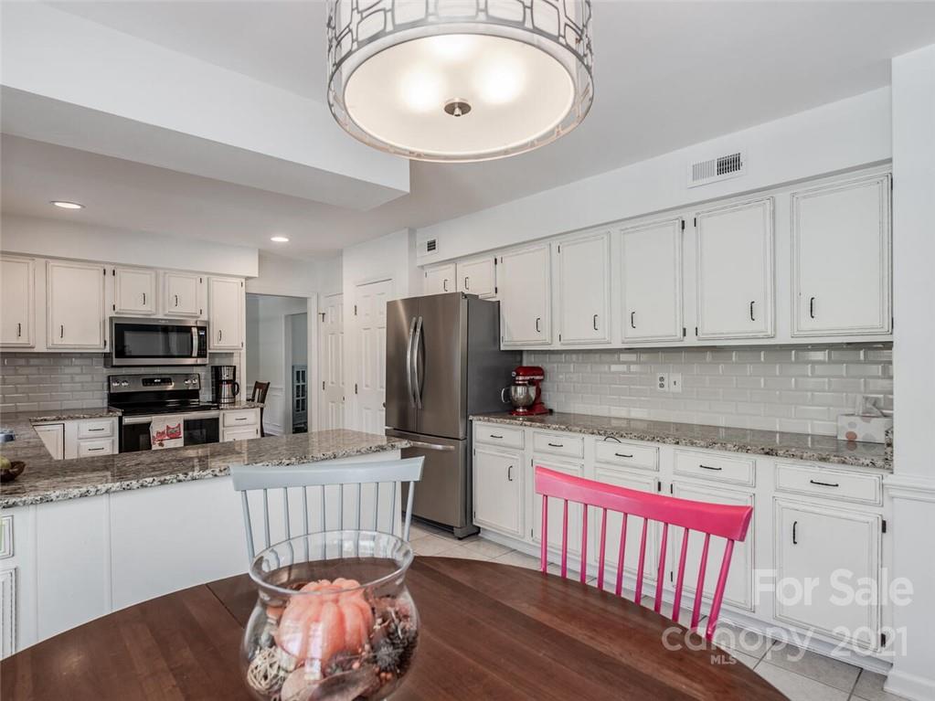 4312 Truscott Road Charlotte, NC 28226 - Photo 15 of 31 a kitchen with stainless steel appliances granite countertop a stove top oven a refrigerator a sink and a dining table with wooden floor