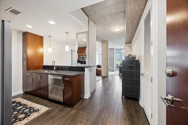 a large kitchen with stainless steel appliances a refrigerator a sink dishwasher a stove and white cabinets with wooden floor