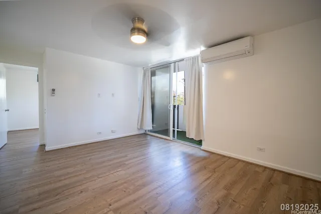 a view of an empty room with wooden floor and a window