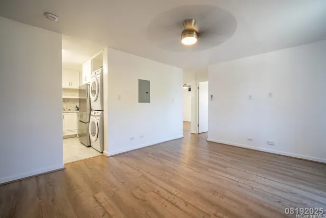 a view of an empty room with wooden floor and a window