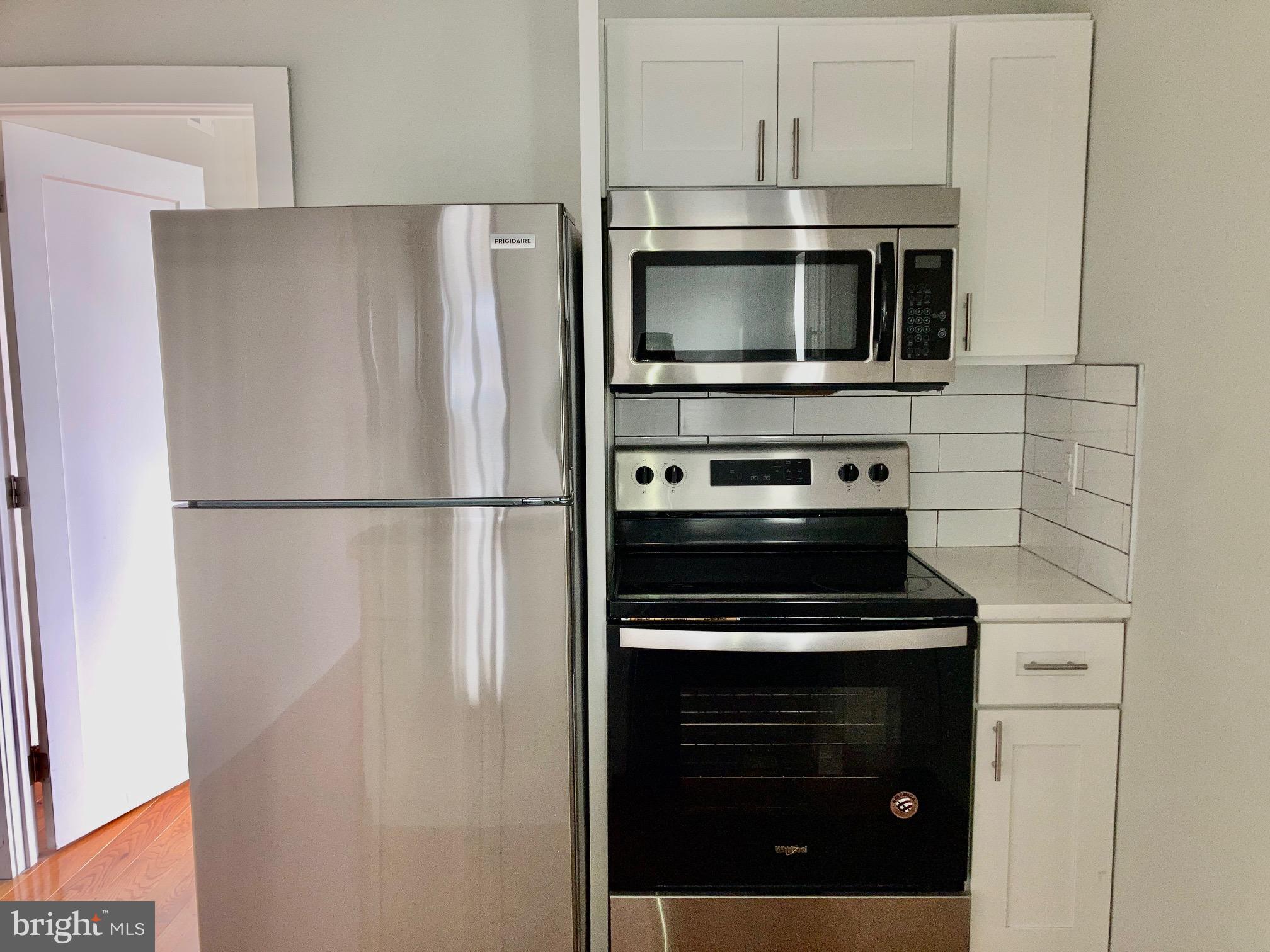 5358 Addison Street, Unit 2 Philadelphia, PA 19143 - Photo 10 of 13 a kitchen with stainless steel appliances a refrigerator stove and microwave