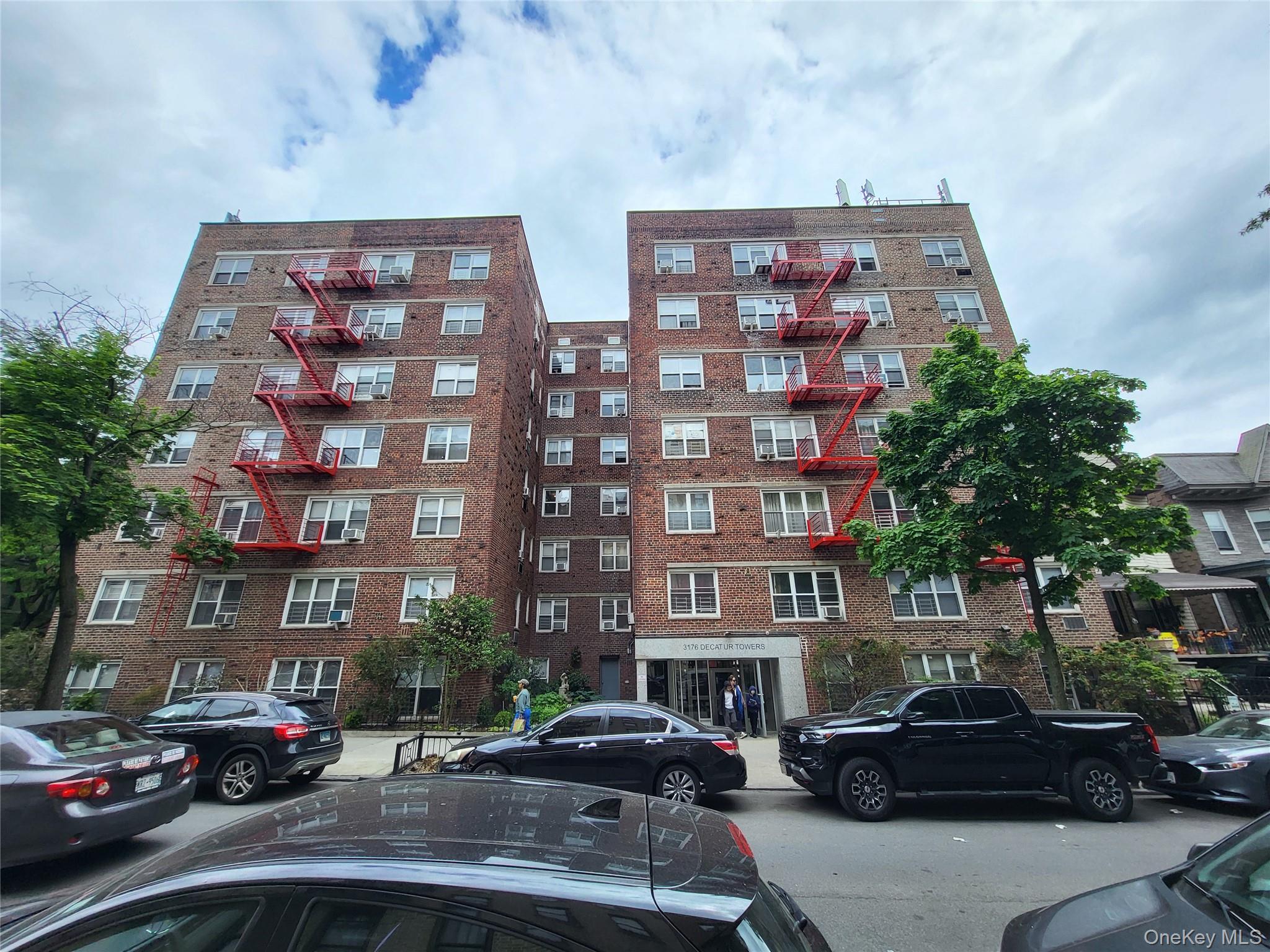 3176 Decatur Avenue, Unit 6H Bronx, NY 10467 - Photo 1 of 12 Brick multi-story building featuring multiple windows and bright red fire escapes