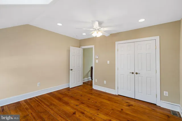 an empty room with wooden floor and a ceiling fan