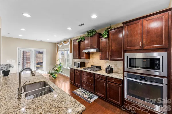 a kitchen with stainless steel appliances granite countertop a stove a sink and a microwave