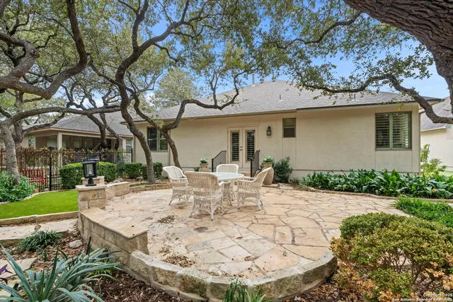 a view of a white house with a table and chairs under an umbrella