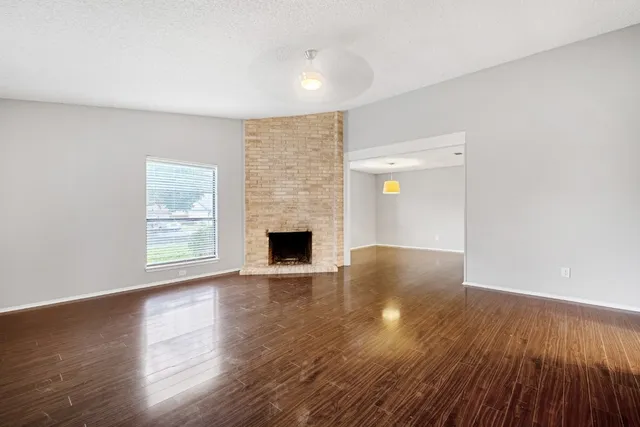 a view of empty room with wooden floor and fireplace