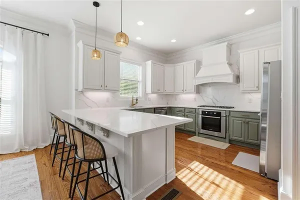 a kitchen with stainless steel appliances granite countertop a stove a refrigerator and a sink with wooden floors