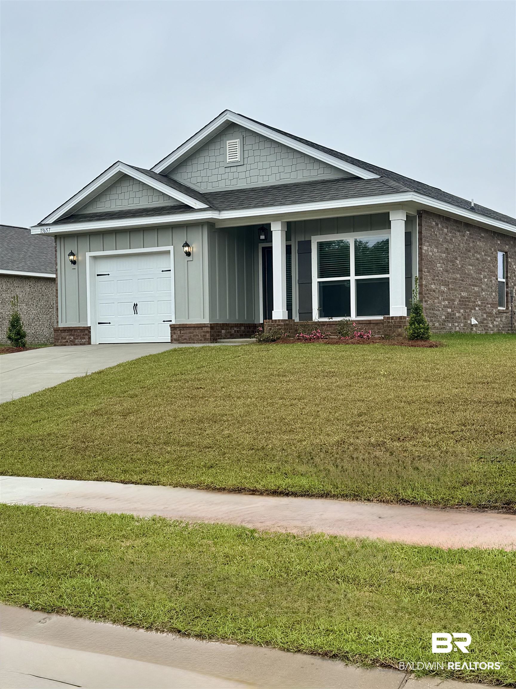 13657 Shea Circle Foley, AL 36535 - Photo 1 of 35 View of front facade with concrete driveway, board and batten siding, a front yard, brick siding, and a garage