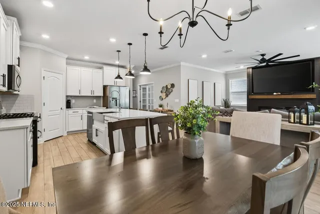 a view of a white house next to a yard with big trees