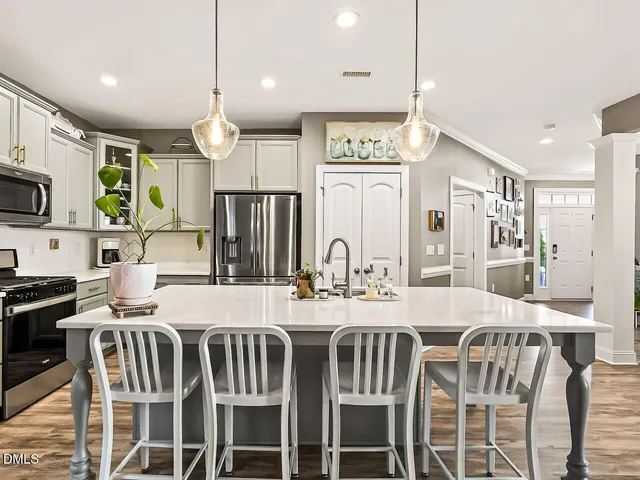 a kitchen with stainless steel appliances kitchen island granite countertop a kitchen island and chairs in it