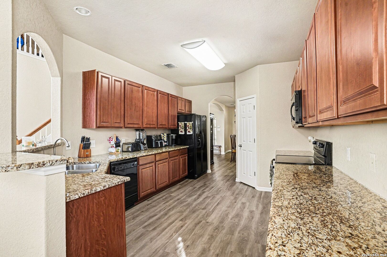 213 Wildcat Cibolo, TX 78108 - Photo 12 of 35 a kitchen with stainless steel appliances granite countertop a refrigerator a sink dishwasher a stove with wooden cabinets and floor