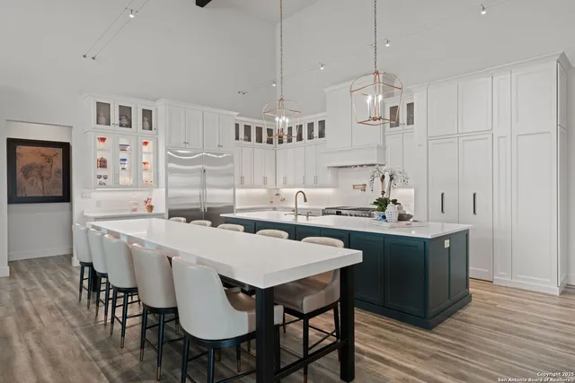 a kitchen with stainless steel appliances granite countertop a sink a stove a dining table and chairs